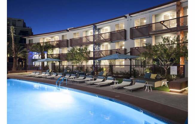 A swimming pool in front of a hotel at night.