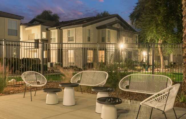 a patio with chairs and tables in front of an apartment building