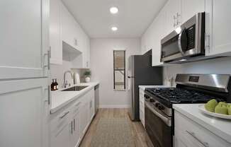 A modern kitchen with white cabinets and stainless steel appliances.