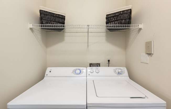 a washer and dryer in a laundry room with two baskets on the wall