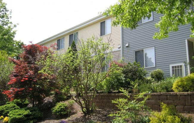 Rear of apartment building with large trees and shrubbery at Yardley Crossing