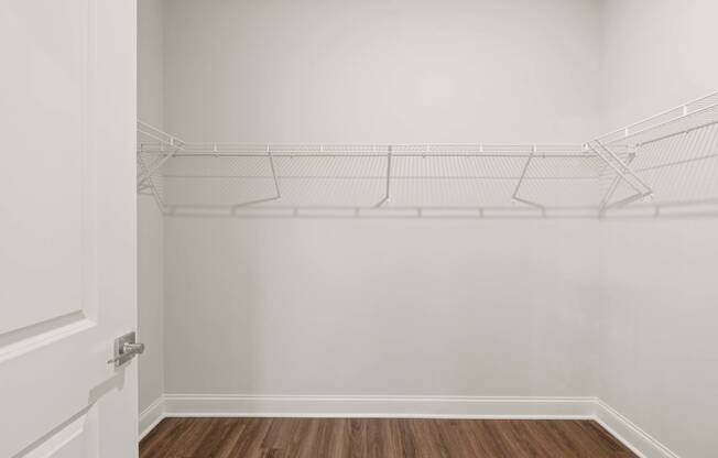 the closet in a bedroom with white walls and a wood floor