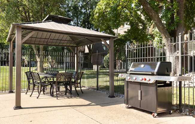 A patio with a grill and a table under a roof.