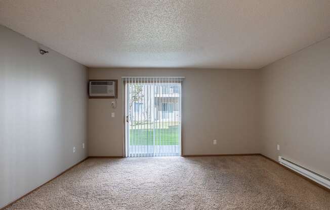 an empty living room with a sliding glass door to a yard