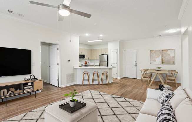 A living room with a white couch, a coffee table, and a television.
