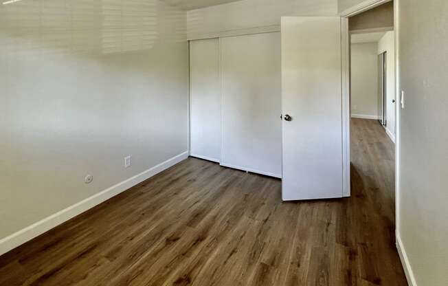 an empty room with white walls and a wooden floor