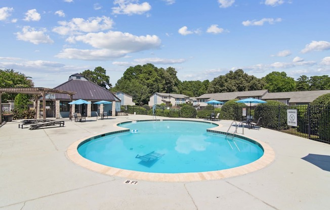 A large outdoor swimming pool surrounded by a fence and trees.