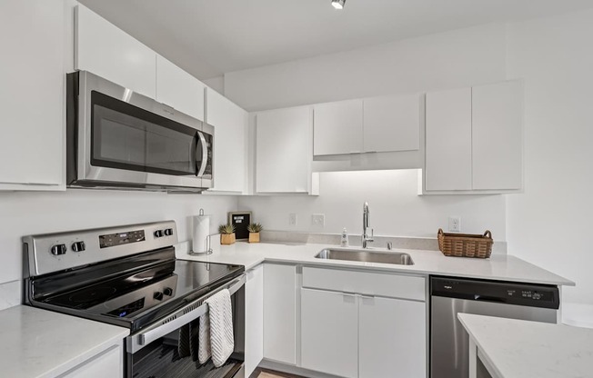 A modern kitchen with white cabinets and stainless steel appliances.