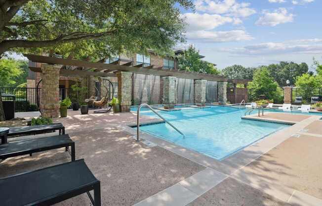 A pool surrounded by a patio with a black bench.