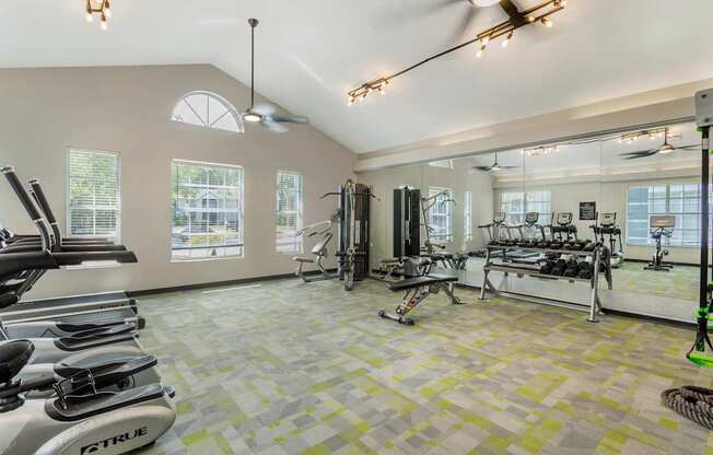 A gym with a variety of equipment including treadmills, weights, and exercise machines.
