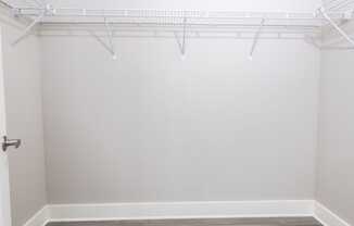 an empty closet with white walls and wood flooring