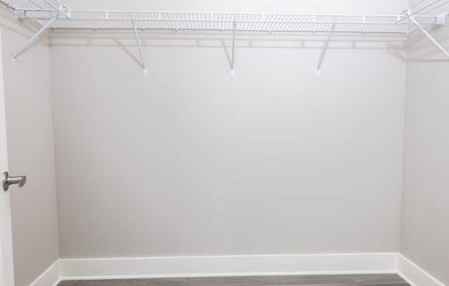 an empty closet with white walls and wood flooring
