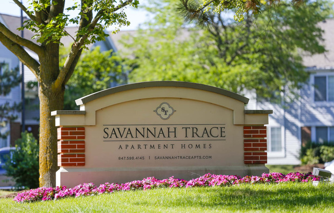 a sign for savannah trace apartment homes in front of a tree