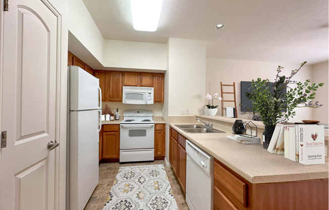 Liberty Commons Apartments, West Valley City, Utah, a kitchen with white appliances and wooden cabinets, dishwasher and pantry.