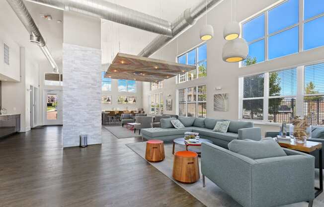 a living room with couches and tables and large windows at Ridge at Thornton Station Apartments, Thornton, 80229