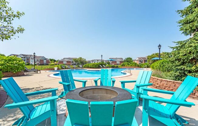 a patio with turquoise chairs and a fire pit
