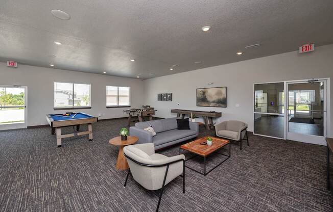 A spacious room with a pool table, couches, and a painting.