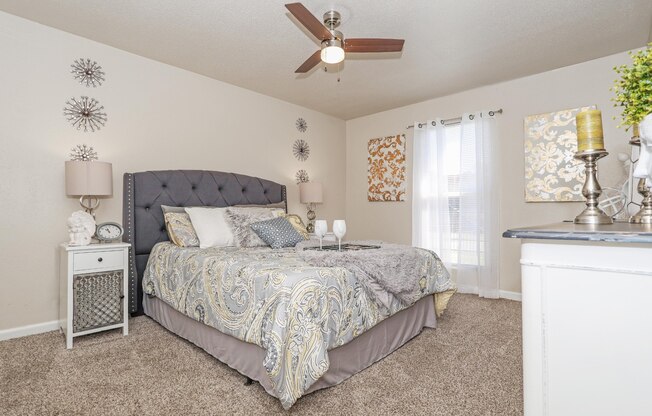 A carpeted bedroom with a large bed and ceiling fan at The Drake in Bossier City, LA