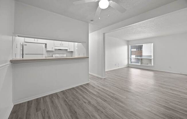 A spacious room with a kitchen area and a ceiling fan.