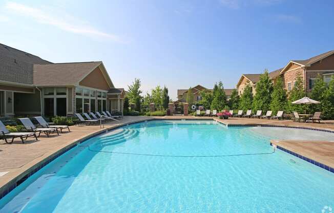 a swimming pool with lounge chairs and buildings in the background at Sovereign at Overland Park, Kansas, 66213