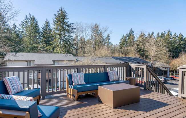 A wooden deck with blue cushions and a bench.