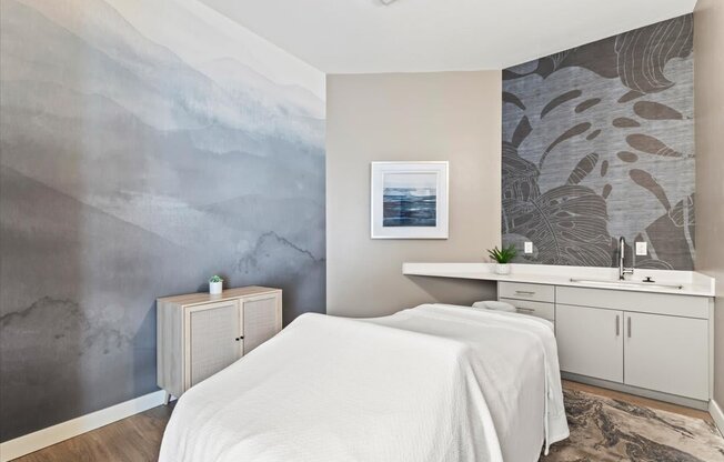 A bedroom with a white bed and a grey wallpapered wall.