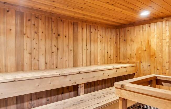 A wooden sauna with benches and a light on the wall.