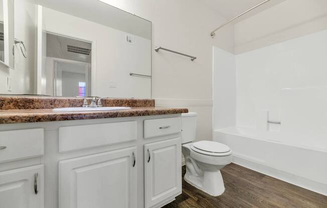 A white bathroom with a marble countertop and wooden flooring at Urban WalkApartments on 6th Avenue, Arizona 85016