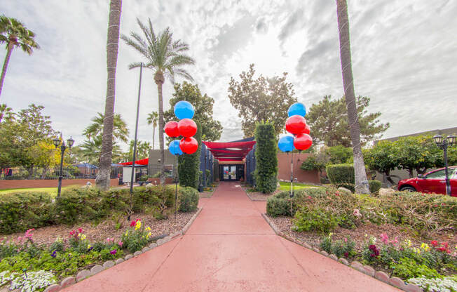 a walkway with colorful balloons at the entrance to a parking lot