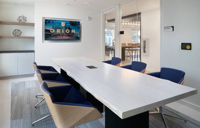 a conference room with a long white table and blue chairs