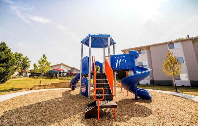 a playground with a slide and climbing equipment in front of a building