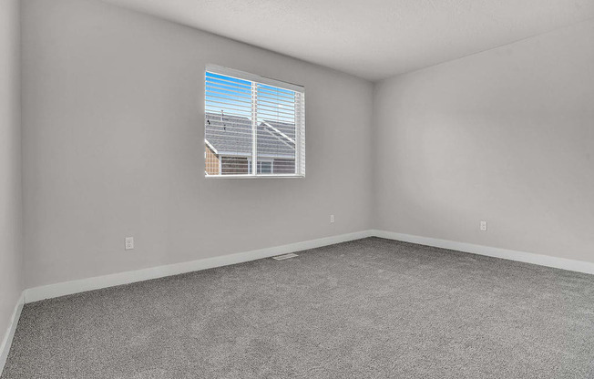 A room with a window showing a view of a house and a utility pole.