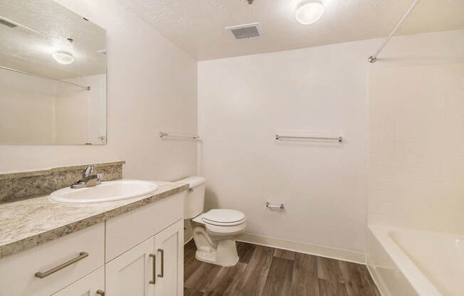 A bathroom with white cabinetry and a sink, toilet, and bathtub at West Hampton Park Apartments in Elkhorn, NE 68022