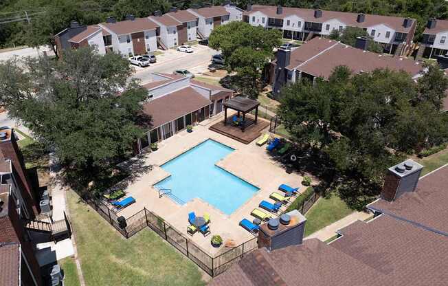 A pool surrounded by a fence and chairs.