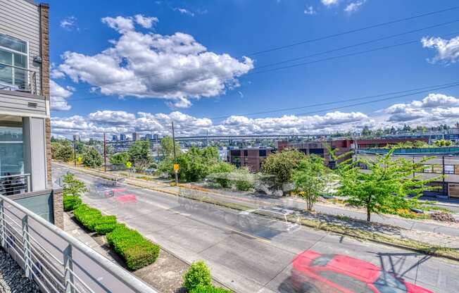 A red car is driving on a road with a building on the left.