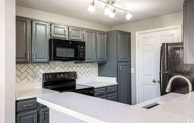 A kitchen with black cabinets and a white counter.