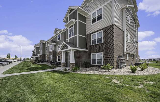 apartment building with grass and sidewalks at Trade Winds Apartment Homes in Elkhorn, NE 68022