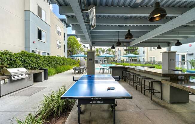 A blue table with a JOOLA logo is in the middle of a patio area.