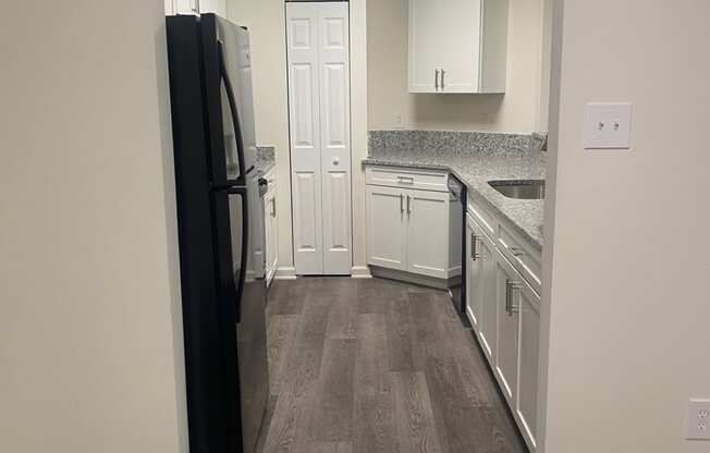 a kitchen with white cabinets and a black refrigerator