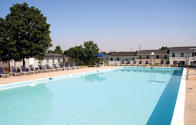 A large outdoor swimming pool with blue water and lounge chairs.