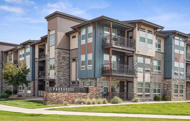 an apartment building with a green lawn and a sidewalk