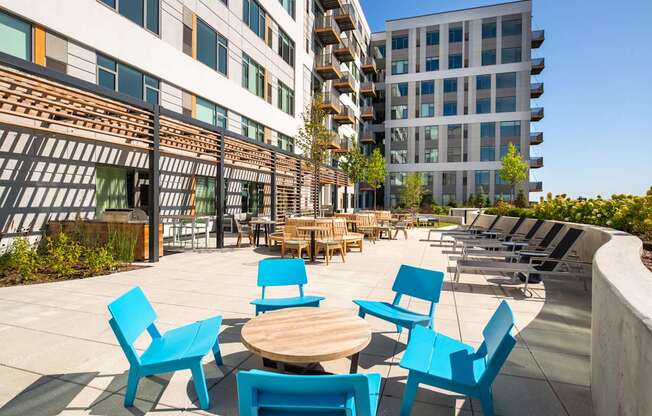 A patio with blue chairs and tables in front of a building.