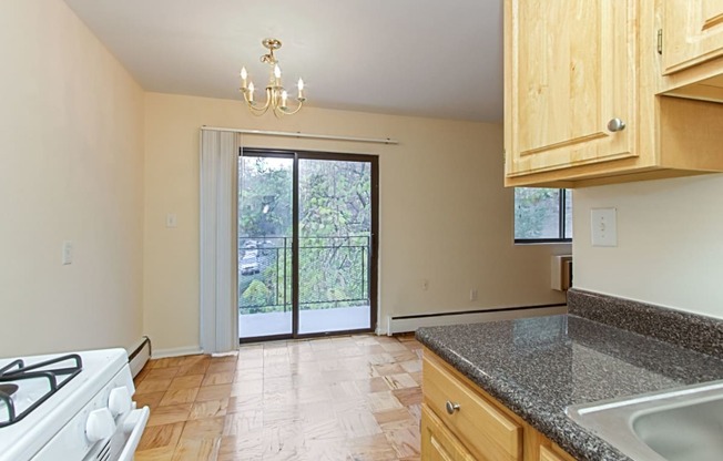 kitchen with wood cabinetry, energy efficient appliances and view of dining area and balcony at fort totten apartments in washington dc