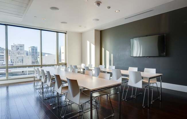 A conference room with a long table and chairs with a city view through the windows.