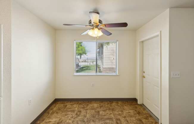 an empty living room with a ceiling fan and a window