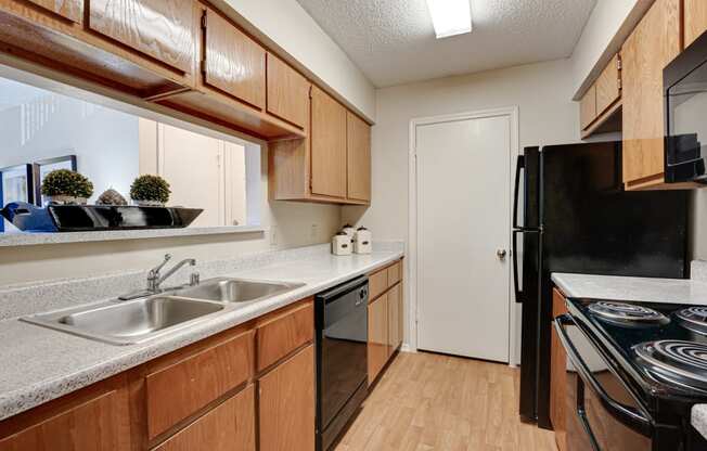 full kitchen with black appliances and wood cabinets at the reserve at walnut creek apartments