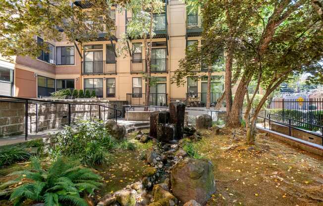 a courtyard with rocks and trees in front of an apartment building