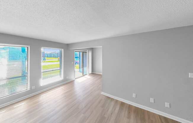 the living room and dining room of an empty house with wood flooring and windows