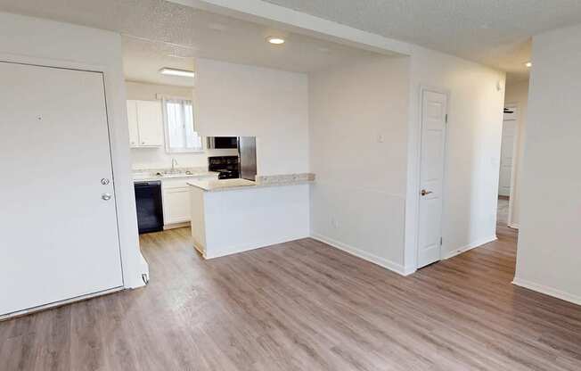 A kitchen with white cabinets and a countertop is visible from the living room.