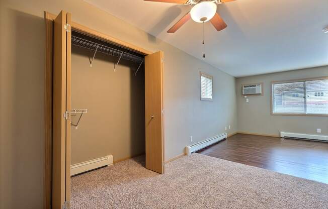 an empty room with a closet and a ceiling fan. Fargo, ND Urban Plains Apartments